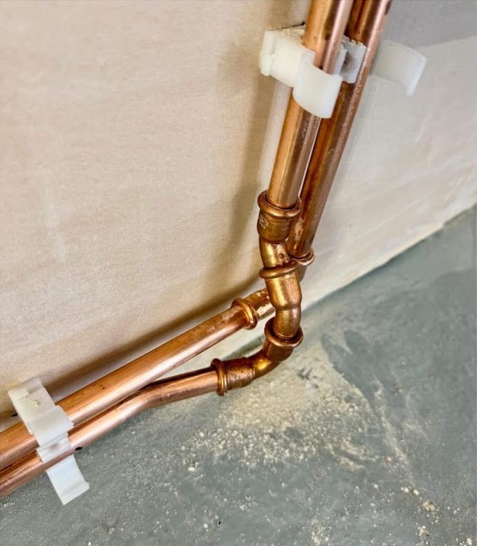Copper pipe connections routed along a wall corner