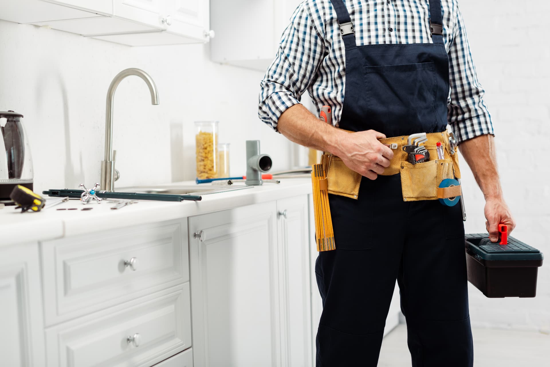 Plumber with tools beside a kitchen sink