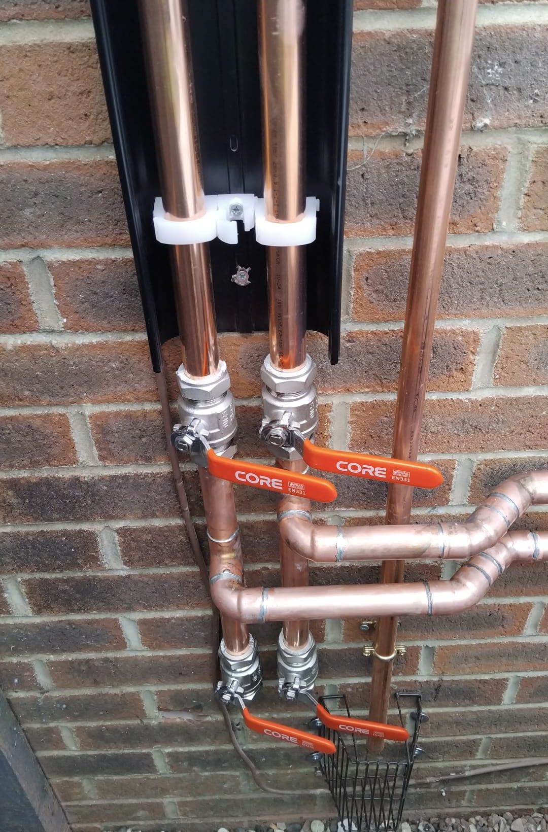 Copper pipework with lever isolation valves mounted on brickwork