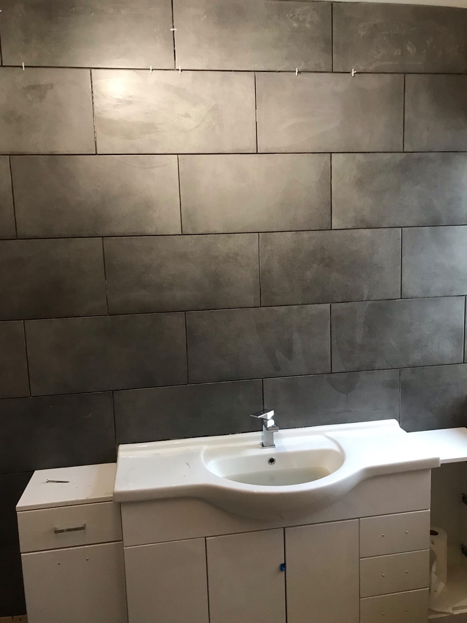 Alternative view of vanity basin and grey tiled bathroom wall