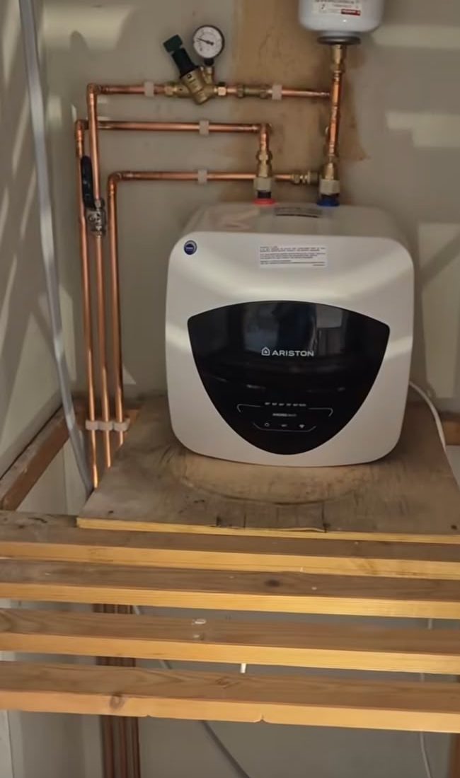 Compact water heater mounted in a timber-lined cupboard