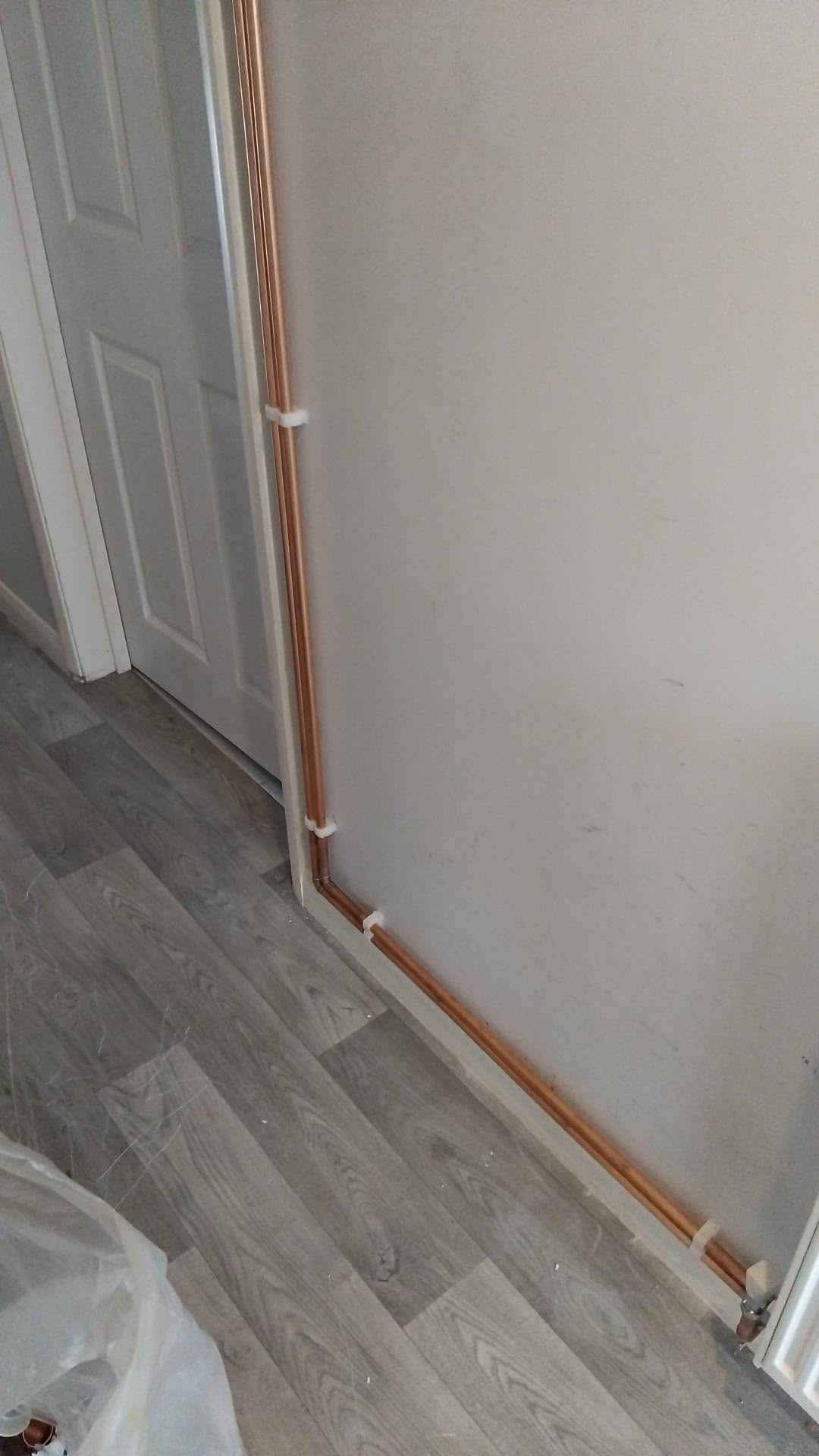 Vertical copper pipe run beside an internal wall